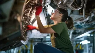 Jeune femme apprentie en train de r&eacute;parer une voiture