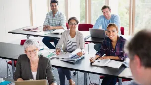 photo d'un groupe en formation, personnes souriantes assises derri&egrave;re des tables