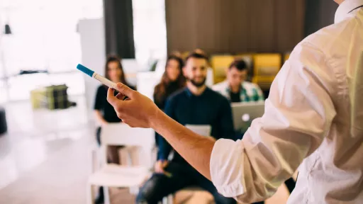 Lecture and training in business office for white collar colleagues. Focus on hands of speaker.