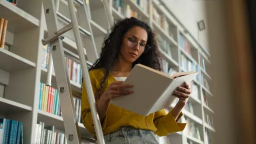 Latina Indian Hispanic woman female student high school university learning girl studying library standing stairs librarian search book textbook pages college teacher learner bookstore buyer archive