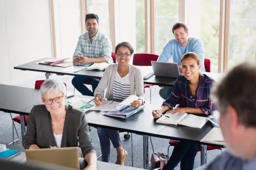 photo d'un groupe en formation, personnes souriantes assises derri&egrave;re des tables